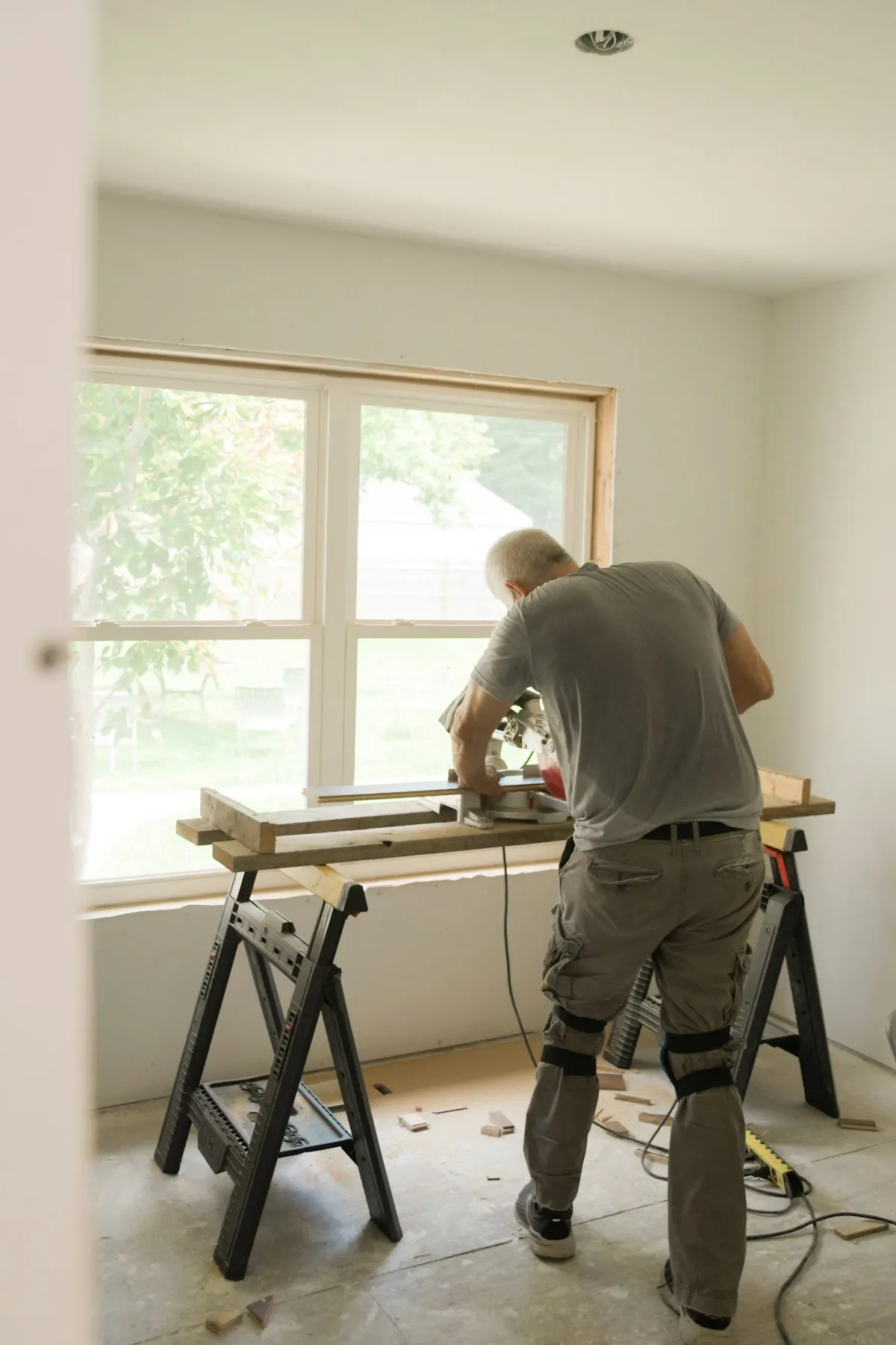 Worker preparing a room beside a trestle workbench