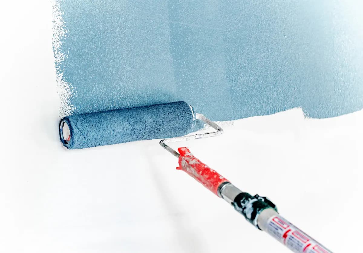 Paint roller applying blue paint to an interior wall