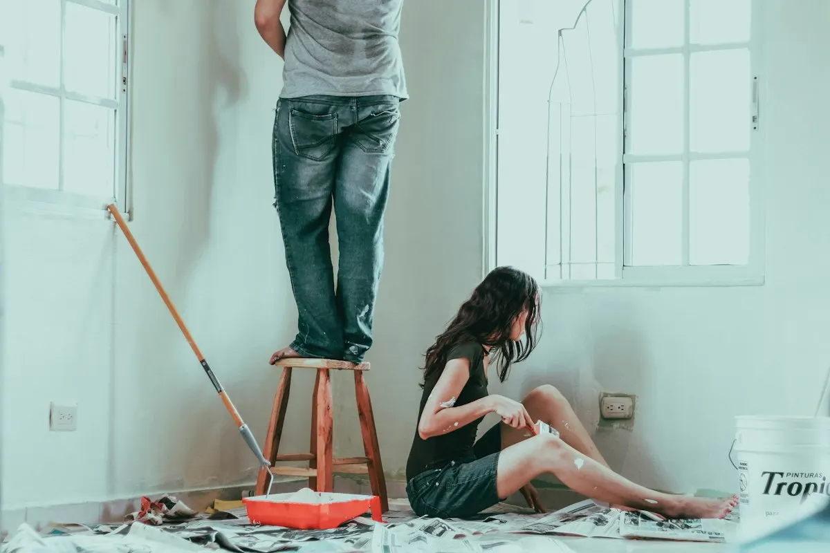 People decorating a room with paint trays and a stepladder