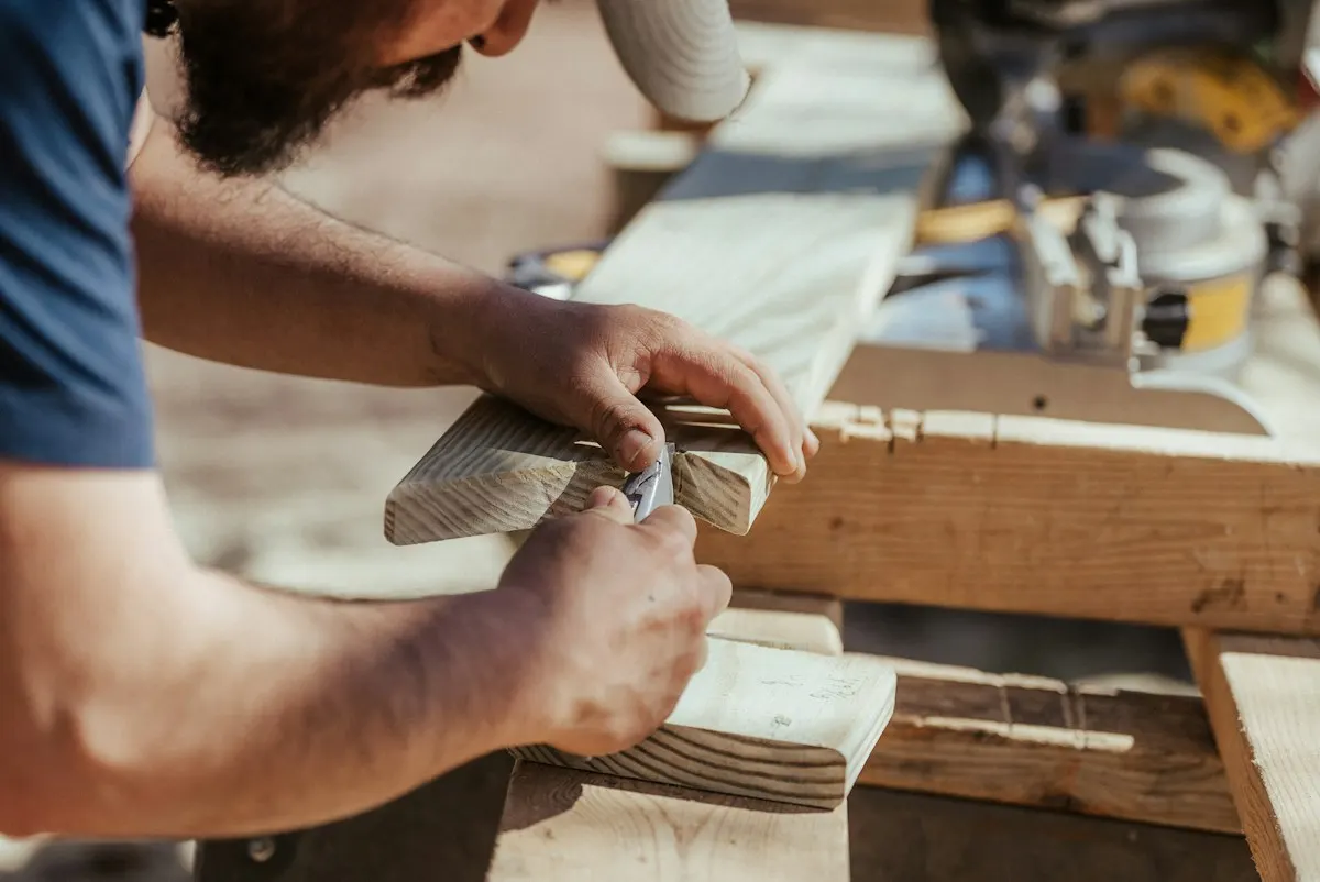 Carpenter measuring a timber board at a workbench