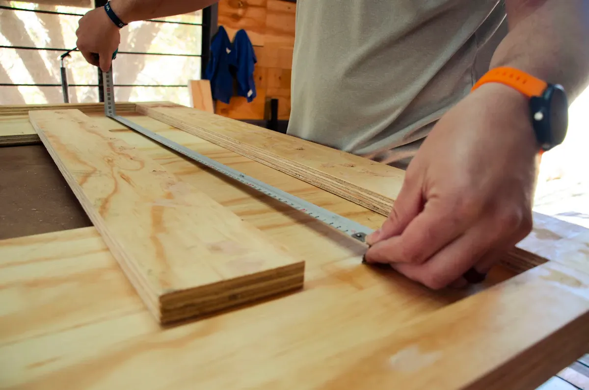 Carpenter marking a timber board with a measuring rule