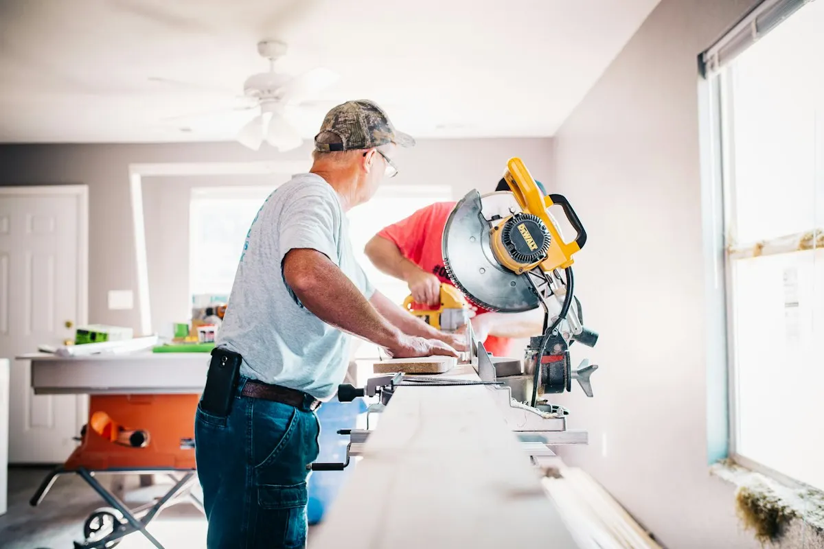 Carpenter cutting timber at a workbench inside a renovation